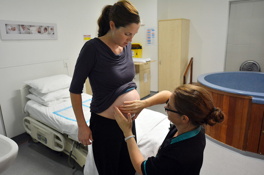 Pregnant woman being checked by midwife