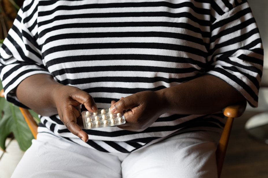 Black woman holds HRT pills
