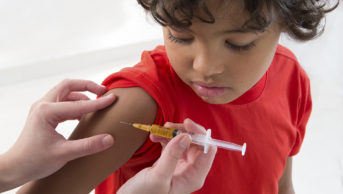 young boy looking at arm about to receive vaccine