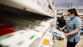 Member of hospital pharmacy staff member orders medications in drawers and shelves