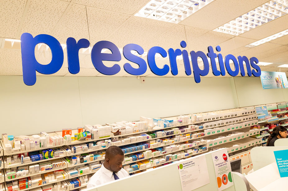 black male pharmacist behind prescriptions counter