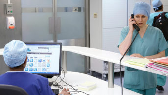 Healthcare professional on computer while other is on phone in hospital