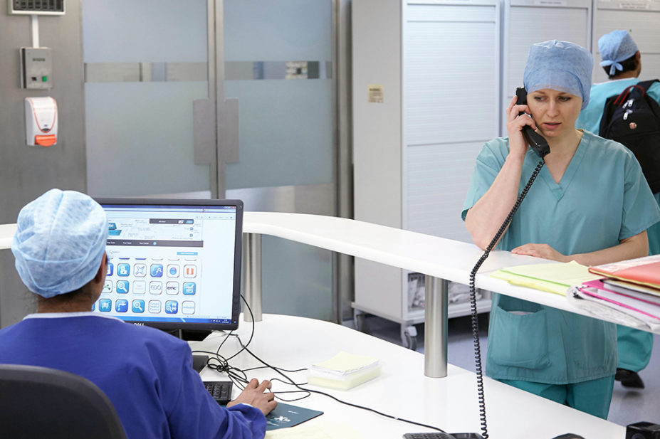 Healthcare professional on computer while other is on phone in hospital