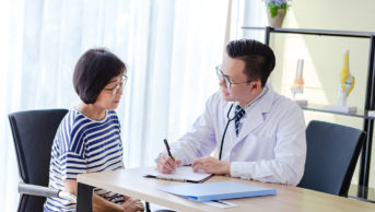 older asian woman talking to doctor