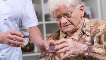 Nurse giving medication to an old woman