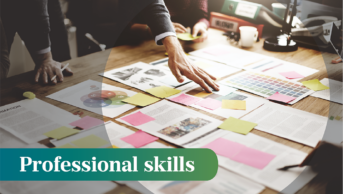 A person leans over a table with lots of papers and sticky notes arranged across, the words