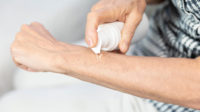 older woman applying hrt gel to forearm