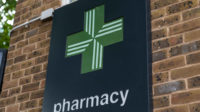 A close up shot of a a green pharmacy cross sign