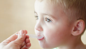 young boy taking medicine on spoon