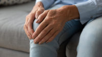older woman holding knee while sat down