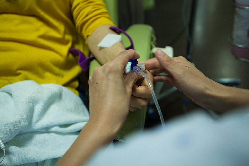 healthcare worker inserting chemotherapy drip into patient's arm