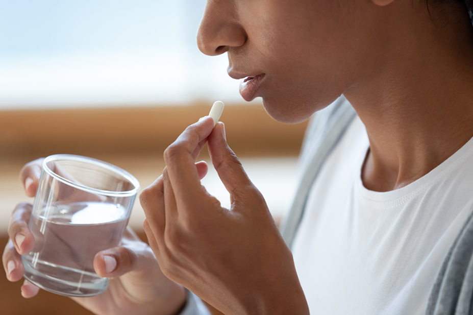 woman taking tablet with glass of water