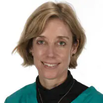 Rachel smiles in front of a white background, wearing a black top and a teal jacket
