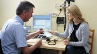 Prescribing antidepressant. General practice doctor (GP) giving a female patient a prescription for drugs to treat depression. He is prescribing the antidepressant drug Sertraline.