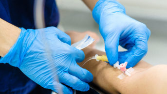 healthcare professional inserting needle into patient's arm
