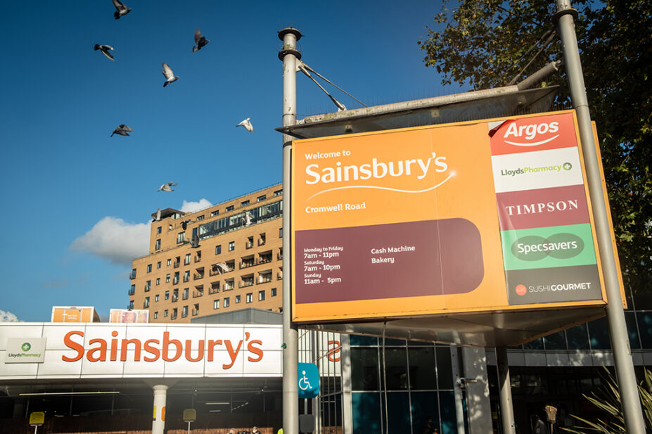 Photo of Sainsburys supermarket on Cromwell Road, Kensington with advertisements for its in-store LloydsPharmacy, Argos, Timpson and Specsavers