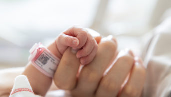 newborn baby's hand holding mother's finger