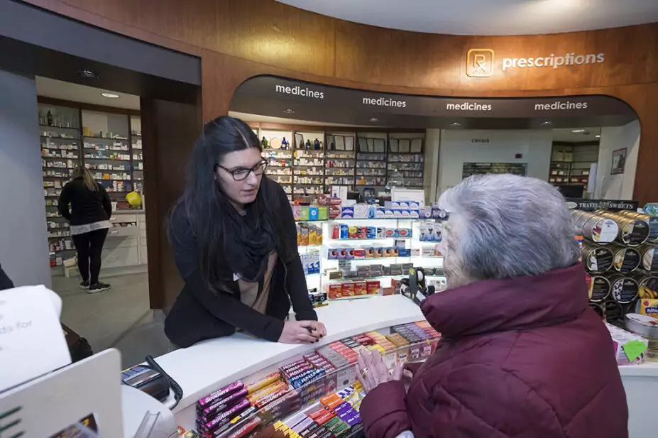 older woman talking to pharmacist at pharmacy counter