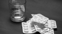 Glass of water, with emptied pill packets alongside.