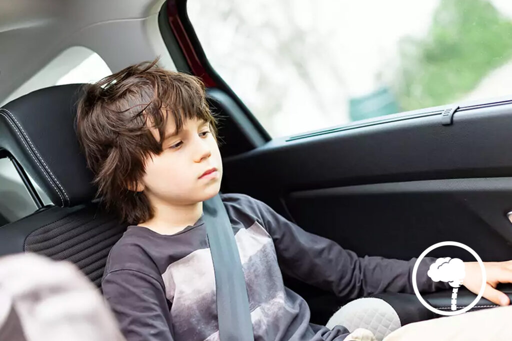 Photo of a child with motion sickness looking uncomfortable in a moving car.