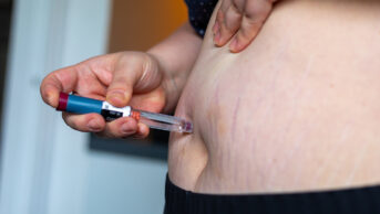 Overweight woman applying injection in stomach