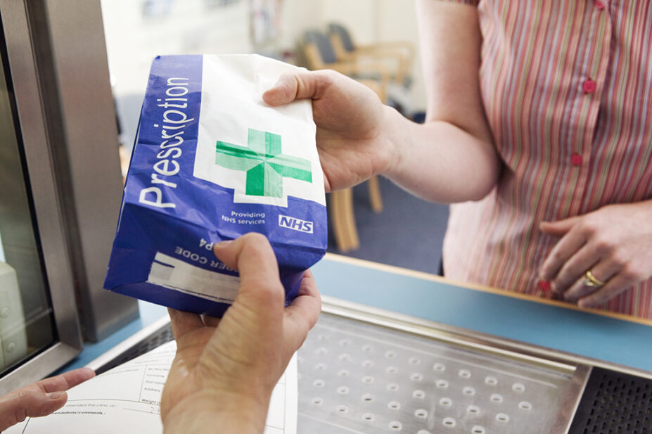 pharmacist handing patient a prescription bag