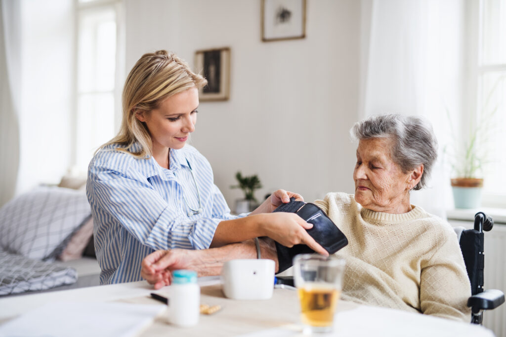 Photo of a female health professional measuring a blood pressure of a senior woman at home.