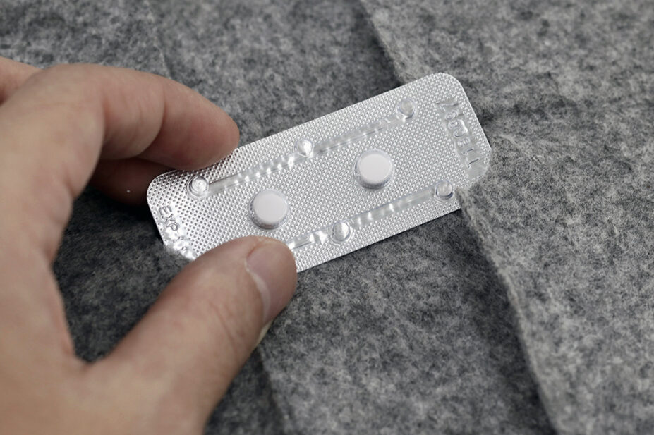 Woman holding two tablets of contraceptive pill or morning after pill in blister pack