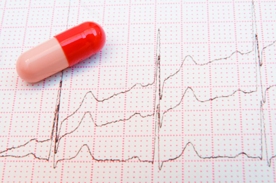 Photo of a pill resting on top of an ECG chart which shows escalating beats