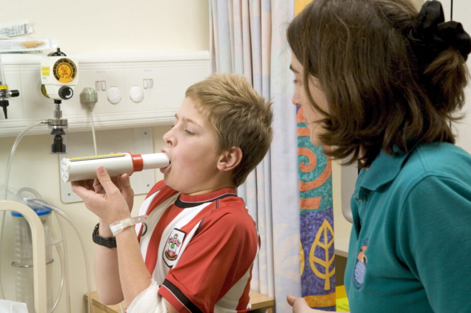 A child in hospital blows into a peak flow meter