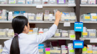 Asian pharmacist stocking shelves