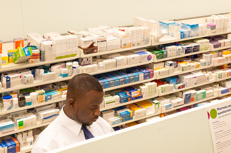 Young pharmacist at prescriptions counter at pharmacy