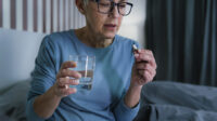 older woman taking tablet sitting in bed