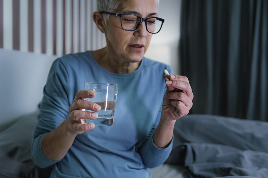 older woman taking tablet sitting in bed