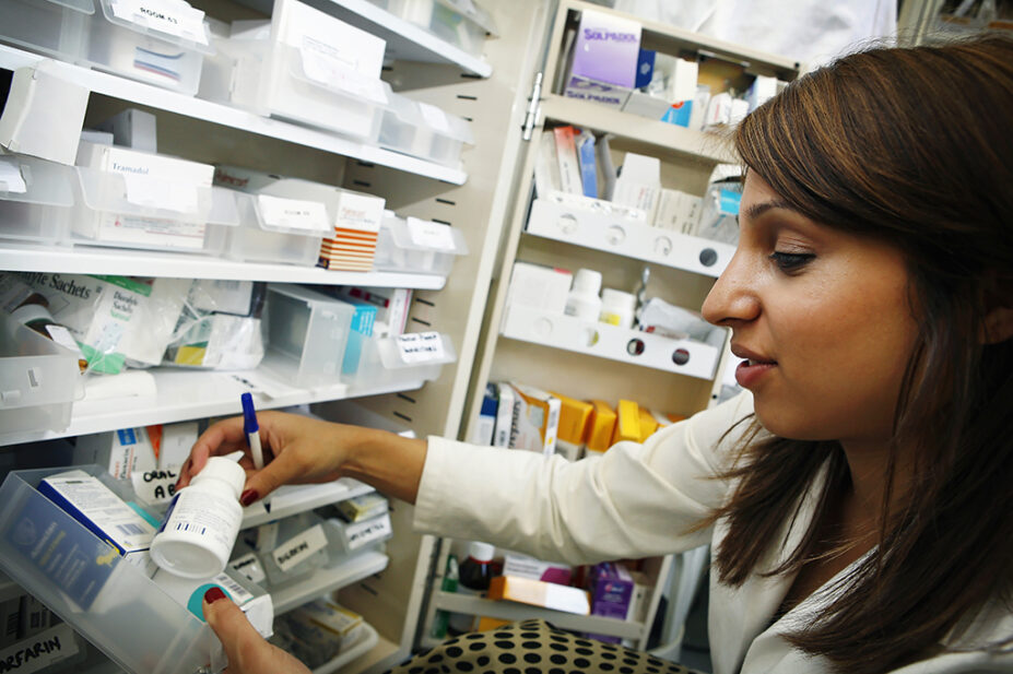 hospital pharmacist selecting medicine from shelf