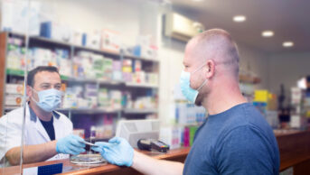 Pharmacy counter during COVID with pharmacist and customer wearing masks
