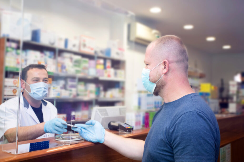 Pharmacy counter during COVID with pharmacist and customer wearing masks