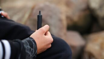 Photo guy of a teen holding a vape in his hands