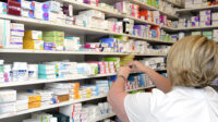 pharmacist taking medicine box off shelf