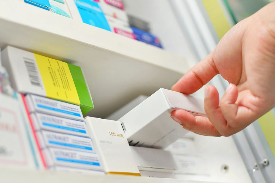 Someone pulling pack of medicines from pharmacy shelf