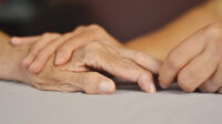 Photo of hands holding and older person's hands with rheumatoid arthritis