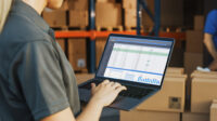 woman using laptop with warehouse in background