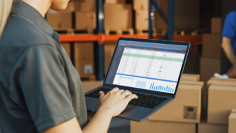 woman using laptop with warehouse in background