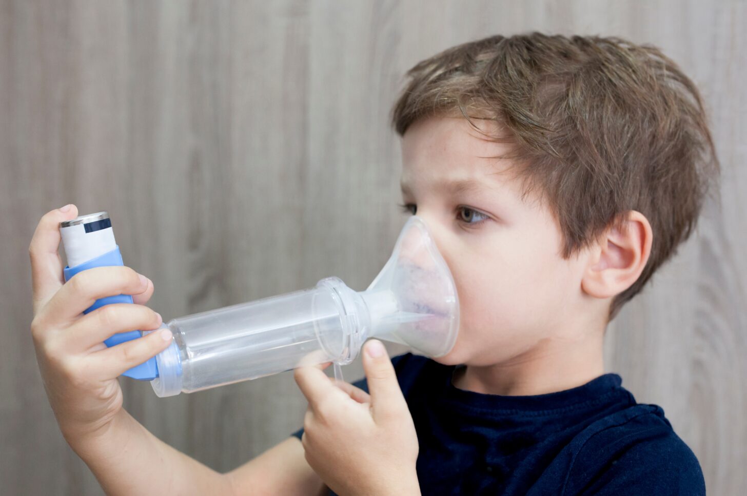 Photo of a child using an asthma inhaler and spacer