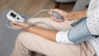 Photo of a woman using a home blood pressure monitor