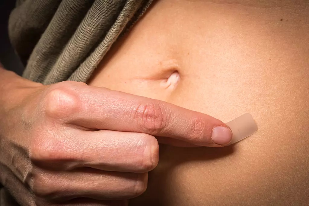 Photo of a woman putting on a hormone patch