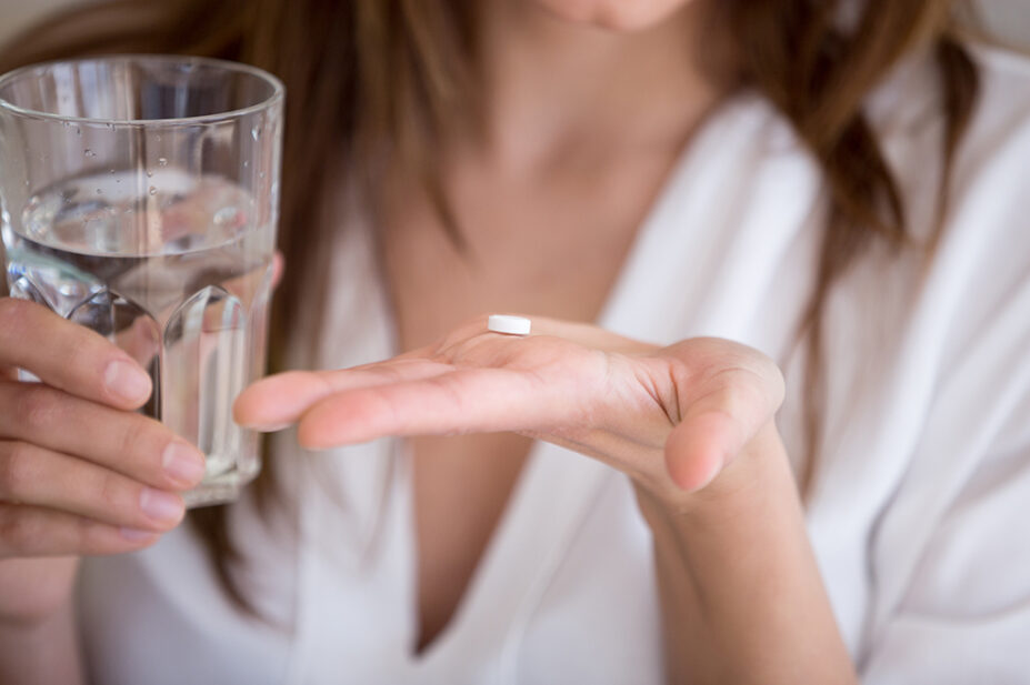 woman taking antibiotic with water