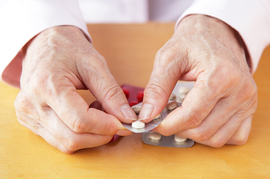 Older woman opening packet of pills