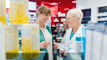 Pharmacist and customer talking happily in pharmacy dispensary