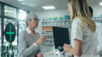 older woman talking to pharmacists at pharmacy counter